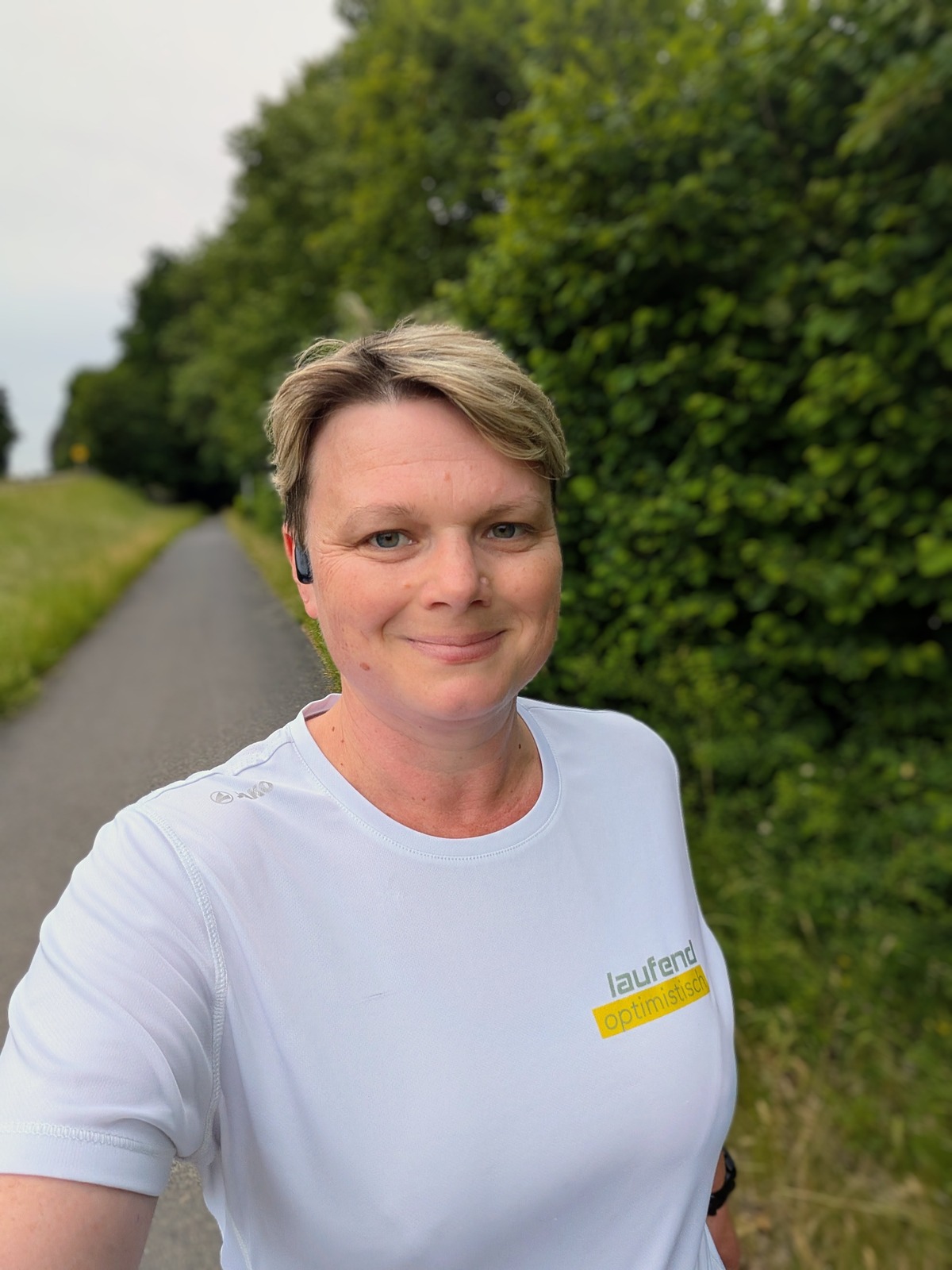Jasmin trägt ein weißes Laufend-Optimistisch-Shirt